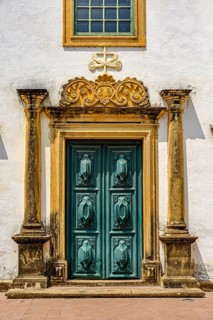Entrance of historic baroque church with large wooden door and ornaments around in the city of
