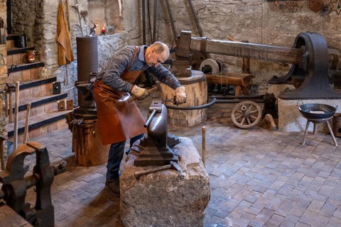 An elderly blacksmith in Salzburg, Austria, skillfully works in his workshop, preserving