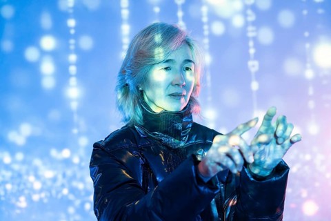 An elderly Asian woman navigates a vibrant virtual metaverse environment, showcasing the