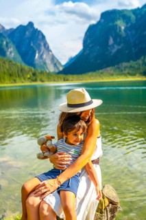 Mother hugging her son while enjoying the breathtaking view of lake dobbiaco and the surrounding