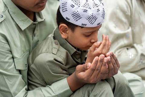 A Muslim child with elders attend to Eid al-Fitr prayer at Eidgah, on March 21, 2026 in Guwahati,