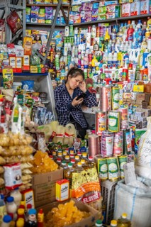 Woman surrounded by many products in her stall, consumption, market stall at Osh bazaar, Bishkek,