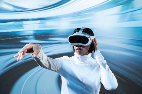 Latin woman in white turtleneck engaging with a virtual environment using VR glasses, reaching out