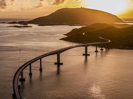 Sommaroy Bridge connecting Kvaloya Island to Sommaroy Island, warm light at sunset, aerial view,