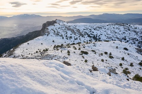 Majestic snowy landscape of Montcabrer, Spain, captures rolling hills covered in snow, dotted with