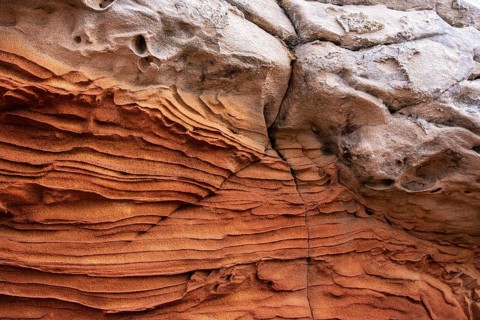 A close-up of sandstone textures revealing intricate layers and natural formations. The earthy