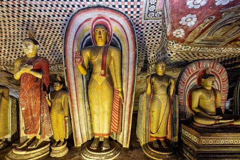 Row of Buddha statues in front of colorful wall paintings and rich details, The cave temple of