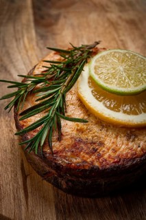 Salmon steak, fried, on a cutting board, top view, rosemary, lemon and lime, homemade, one serving,