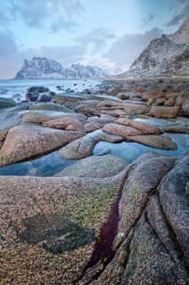 Rocks on beach of fjord of Norwegian sea in winter on sunset. Utakliev beach, Lofoten islands,