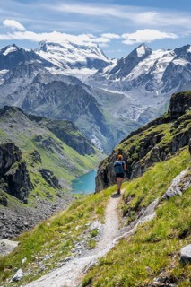 Hiker on hiking trail, mountain lake Lac de Louvie with glaciated summit of the Grand Combin, Val