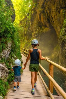 Mother and son wearing helmets, enjoying a walk through the scenic vintgar gorge in slovenia,