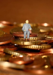 Miniature man sitting among euro coins, North Rhine-Westphalia, Germany