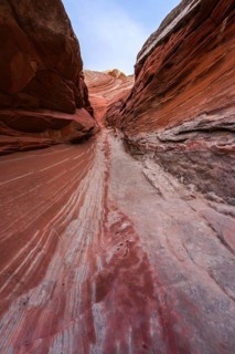 Vibrant red and orange striated sandstone walls form a narrow canyon path in White Pocket, Arizona,