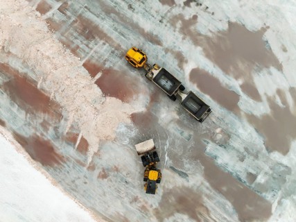 Excavator and lorry at a harvesting pan of the Walvis Bay Salt works. Aerial view. Drone shot.