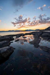 Clouds reflected in a small pond on a rocky coast, coastal landscape at sunset, Henningsvær,