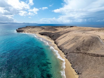 Coast with Playa Caleta del Congrio beach and blue sea, arid landscape of Los Ajaches Natural Park,