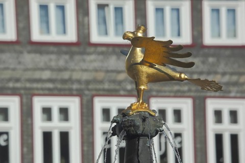 Golden heraldic animal with crown, eagle figure with wing, market fountain, water jets, market