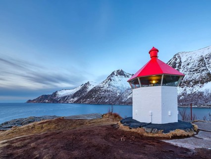 Small lighthouse at the end of Husøy island with a view across the fjord to the sea, Senja island,