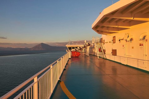 Ferry deck with a view of the sea and a mountain in the evening light, New ferry port in southern