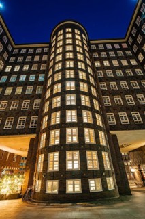 Illuminated brick facade of a tall office building with many windows, taken at night, Hamburg,