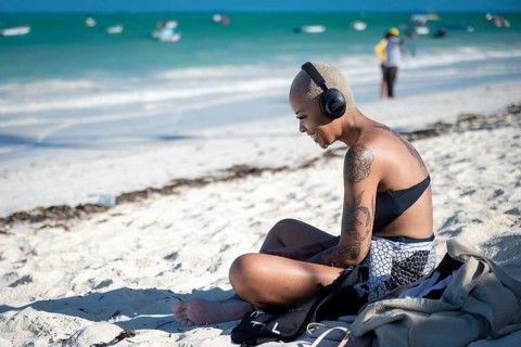 PAJE, ZANZIBAR - OCTOBER 18, 2025: A young woman with tattoos sitting on a white sand beach,