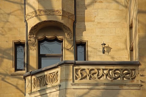 House façade and balcony with decorated balustrade on Art Nouveau villa, decorations, yellow