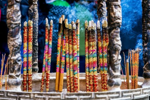 Colorful incense sticks enveloped in smoke at a Taoist and Chinese Buddhist temple in Macau,