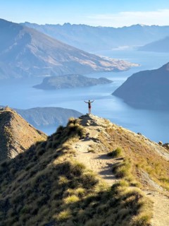 Person with outstretched arms on the hiking trail to Roys Peak Lookout, Lake Wanaka, Wanaka, South