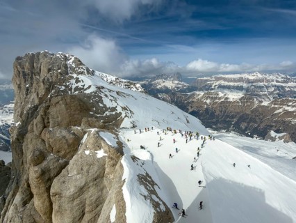 View of the snow-covered Marmolta (3343 m) with skiers in the foreground and clouds in the