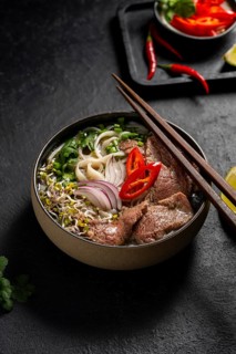 A bowl of Vietnamese Beef Pho Noodle Soup (Pho Bo) featuring slices of tender beef, rice noodles,