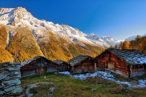 Alpine huts in the Val d'Hérens, behind them snow-covered Valais Alps, Canton Valais, Switzerland