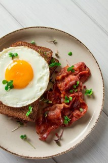 Breakfast, fried egg with bacon, micro-green, on a light background, no people, selective focus