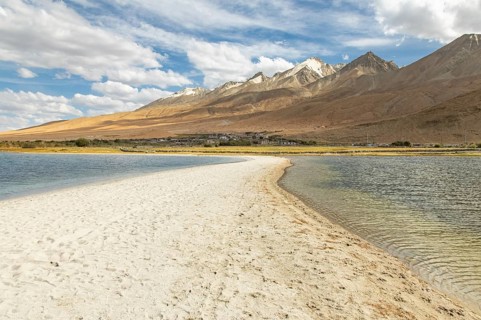 A stunning view of Pangong Tso lake in Ladakh, India, showcasing clear blue waters, a sandy