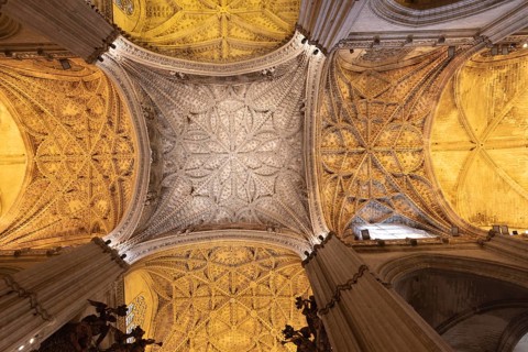 Majestic Gothic vault with detailed decorations and warm lighting, Seville, Andalusia, Spain