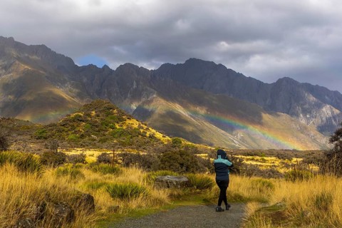 A woman in a winter coat explores the breathtaking autumn landscape of Mount Cook, New Zealand.