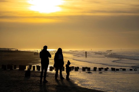 Winter on the North Sea, sunset at sea, beach walkers, coastal protection, through wooden posts,