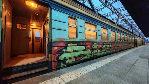 A train with graffiti stands on the platform with open doors and cozy lights, Yerevan, Armenia