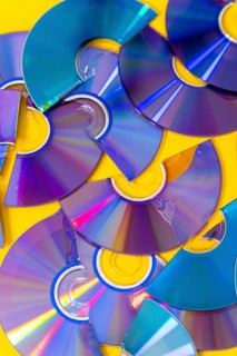 Top view of cut CDs and DVDs against a yellow background