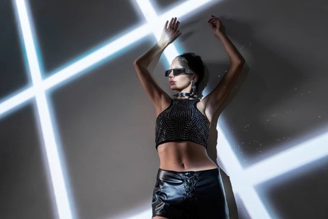 A stylish woman models futuristic cyberpunk attire against a backdrop of intersecting neon lights.