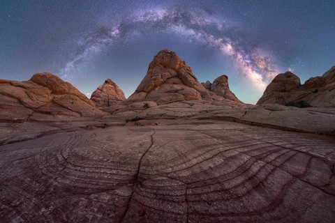 A stunning capture of the Milky Way arching across a clear night sky over unique rock formations in