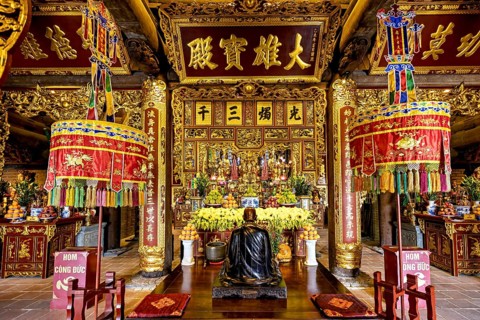 A richly decorated Asian temple with a Buddha statue and colourful decorations in red and gold,
