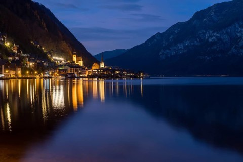 The enchanting village of Hallstatt, surrounded by majestic mountains, is beautifully illuminated