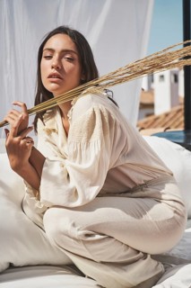 Chic summer vibe on a rooftop A serene woman embraces tranquility, holding decorative plants, in