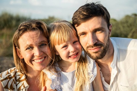 A joyful family of three enjoying a sunny day at the beach in Italy, capturing precious moments and