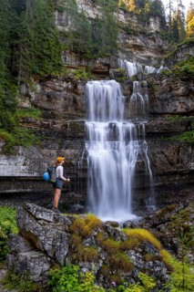 Young pretty hiker standing on rocks in front of Cascata di Mezzo waterfall, long exposure,