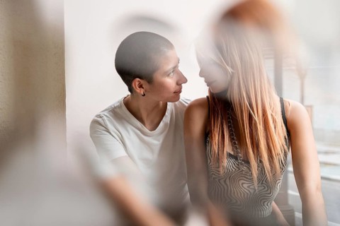 Intimate and candid capture of a lesbian couple sharing a tender moment in a softly lit room. They