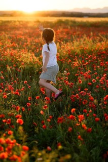 Back view of unrecognizable girl joyfully running in a lush field filled with blooming Papaver
