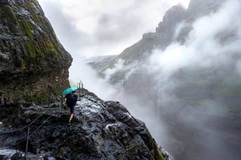 Hikers on a rocky hiking trail Clouds covered in mystical rock gorge with waterfalls, hike to