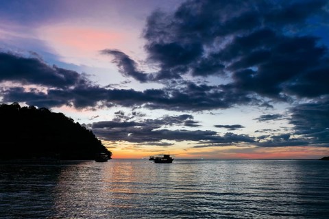 Traditional boats gently float on the tranquil waters of Koh Rong Island, Cambodia, as the sun