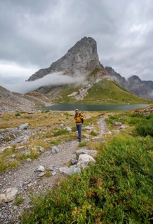 Mountaineers on a hiking trail with a view of rocky cloudy mountains and Wolayersee, hiking trail